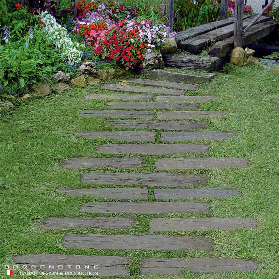 Camminamento con assi in legno a zig zag che conduce a laghetto artificiale con ponte per attraversarlo