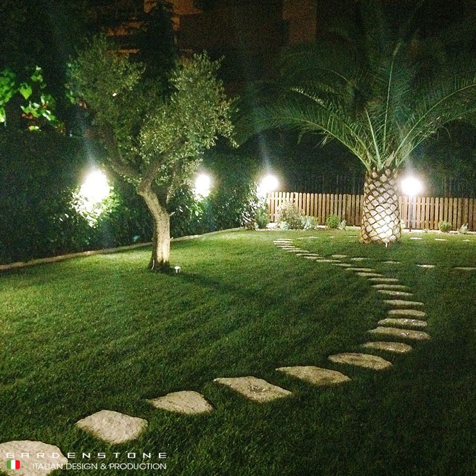 Camminamento irregolare da giardino con piastre in finta pietra distanziate illuminato grazie a faretti luminosi