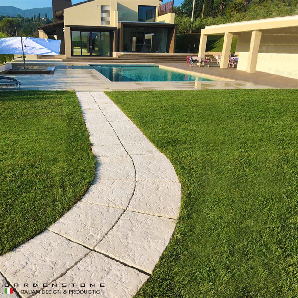Camminamento a curva in finta pietra che conduce a piscina